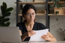 Serious professional woman reviewing contract documents at a desk, representing the importance of understanding contractor agreement terms.